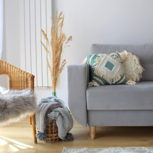 Poszewka boho z frędzlami szałwia salon boho, poszewka szałwia, poduszka szałwia boho z frędzlami, zielona poszewka boho, szara sofa, zielone dodatki w salonie, poduszka dekoracyjna z kremowa aplikacja, poduszka szałwia makrama, macrame boho sage pillow, poduszka makrama szałwia 40x40 cm